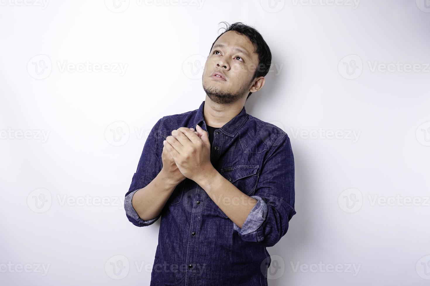 kalme spirituele knappe aziatische man die bidt met gesloten ogen. serieuze vreedzame jonge man met de handen ineen mediteren. geloof concept foto