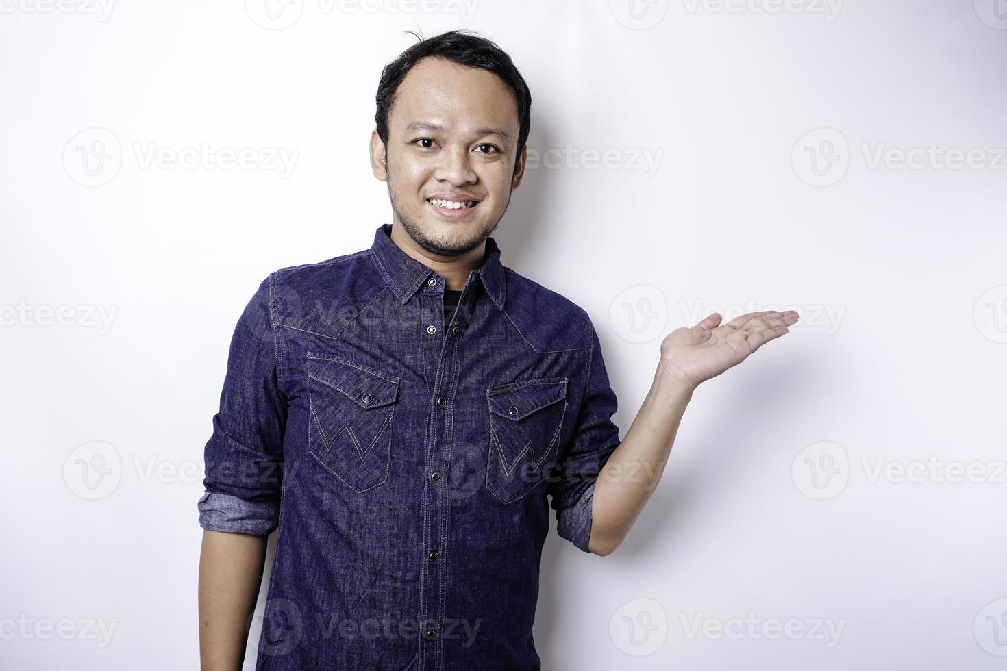 opgewonden Aziatisch Mens vervelend blauw overhemd richten Bij de kopiëren ruimte naast hem, geïsoleerd door wit achtergrond foto