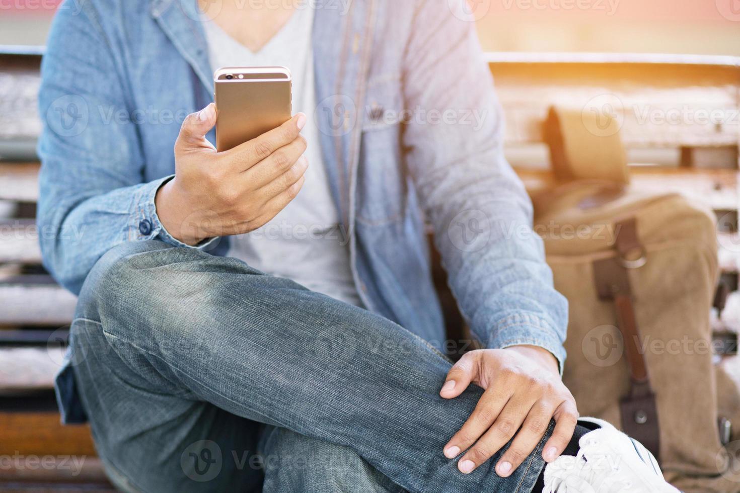 jonge man draagt een geruit overhemd. close-up hand gebruiken op mobiele telefoon tijdens rust op de bank. zittend in het kijken naar bericht op mobiele smartphone tijdens pauze ontspannen. zachte focus. foto