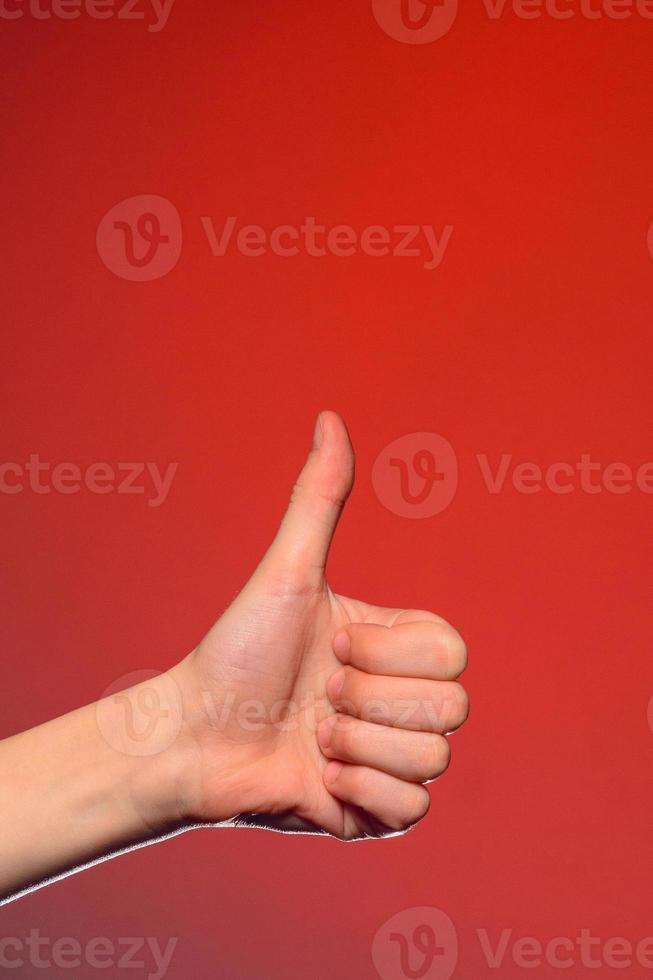 detailopname van een hand- met een vingernagel omhoog van een geïsoleerd Aan een rood achtergrond foto