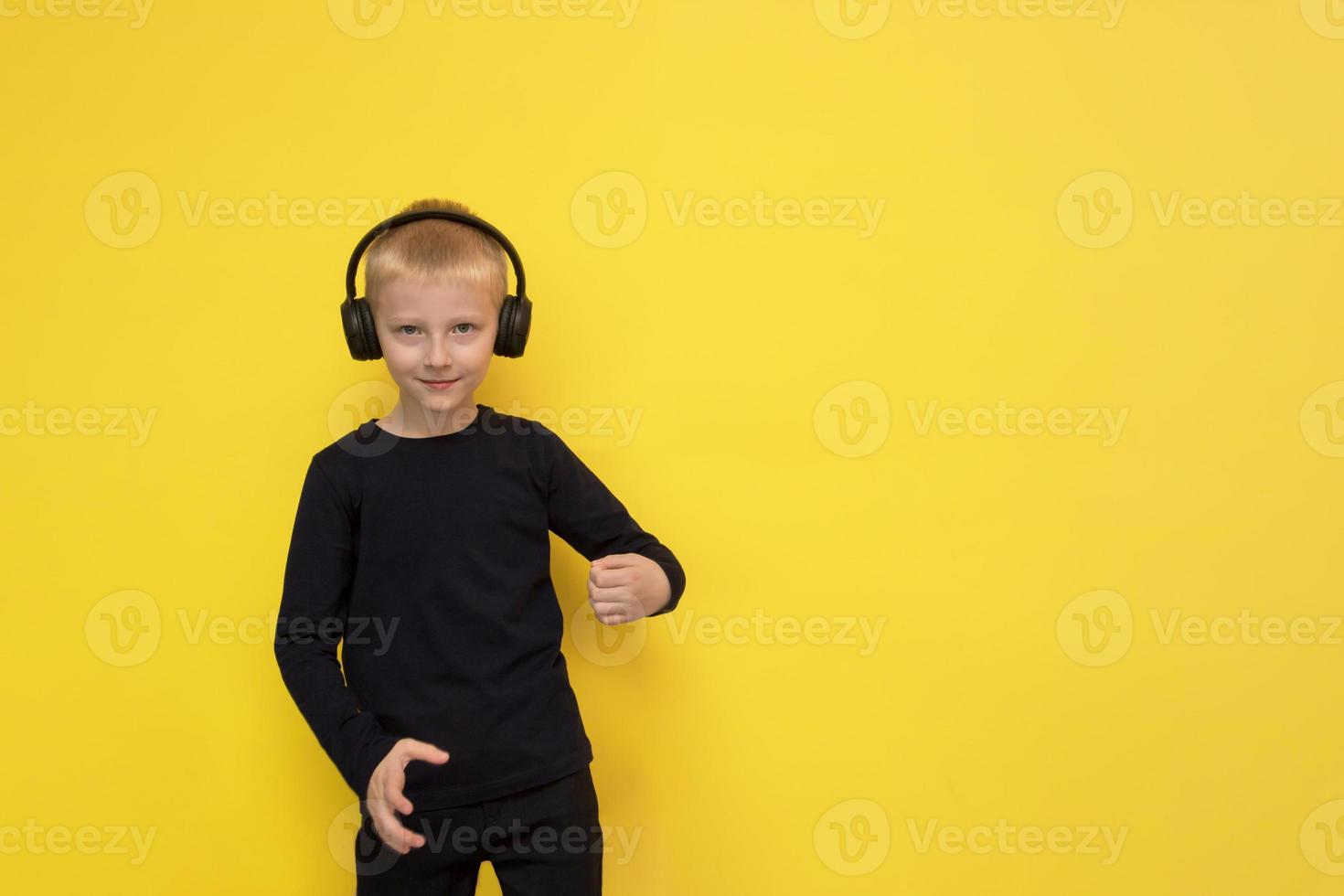 jongen luistert naar muziek- met hoofdtelefoons en dansen Aan een geel achtergrond met kopiëren ruimte foto