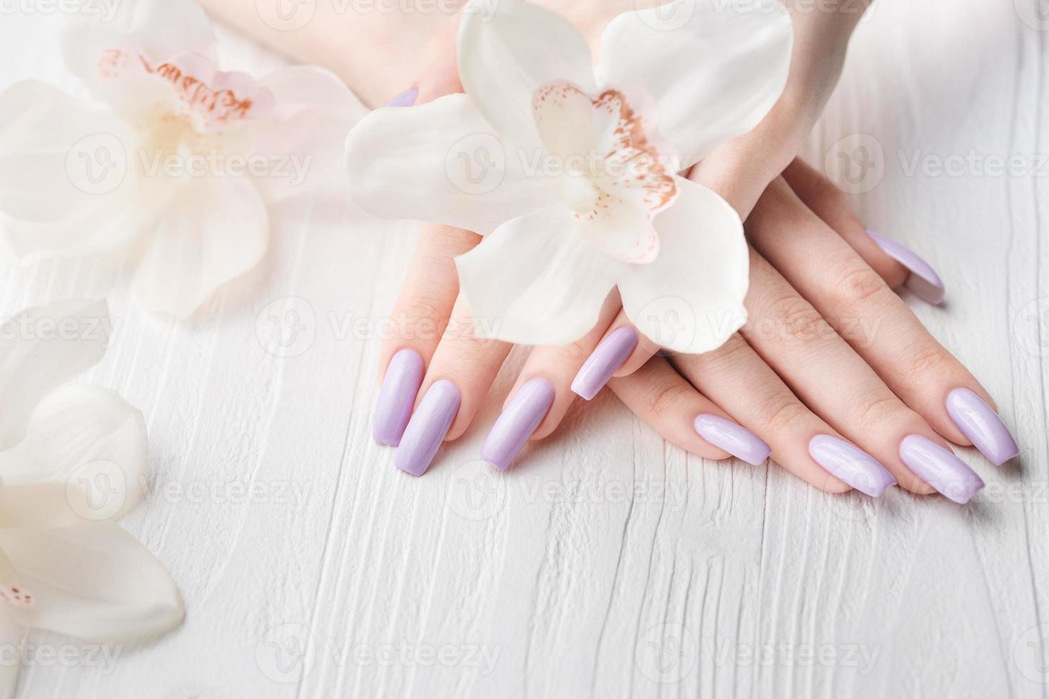 meisjes handen met delicaat Purper manicure en orchidee bloemen foto