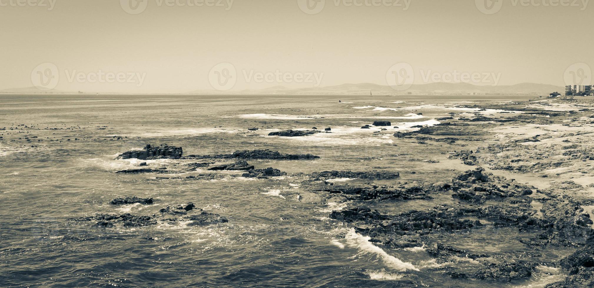 sterke golven, stenen en zeekliffen, zeepuntpromenade in kaapstad, zuid-afrika. foto