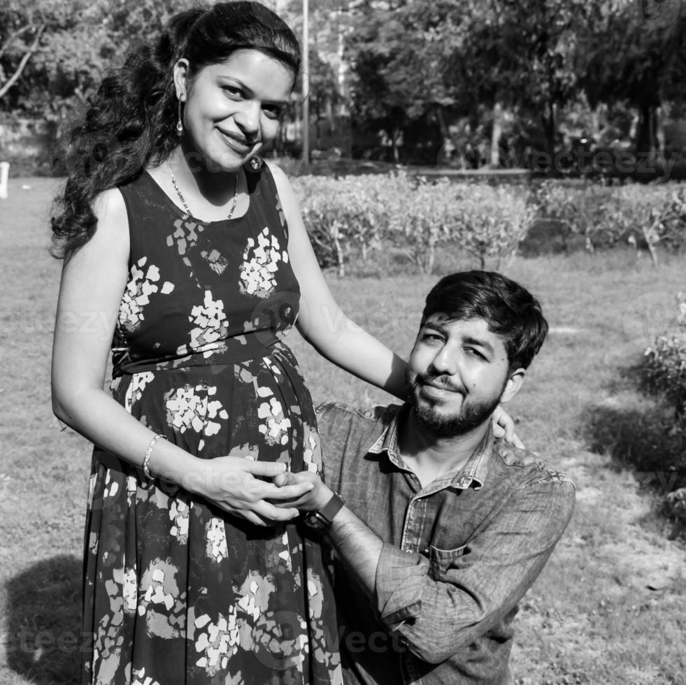 indiase paar poseren voor zwangerschaps baby shoot. het paar poseert in een gazon met groen gras en de vrouw pronkt met haar babybuil in de Lodhi-tuin in New Delhi, India foto