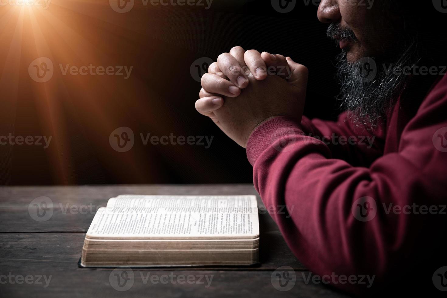 handen gevouwen in gebed Aan een heilig Bijbel in kerk concept voor vertrouwen, geestelijkheid en geloof, Mens bidden in ochtend. Mens hand- met Bijbel bidden. persoon christen wie geloof in Jezus aanbidden in donker. foto