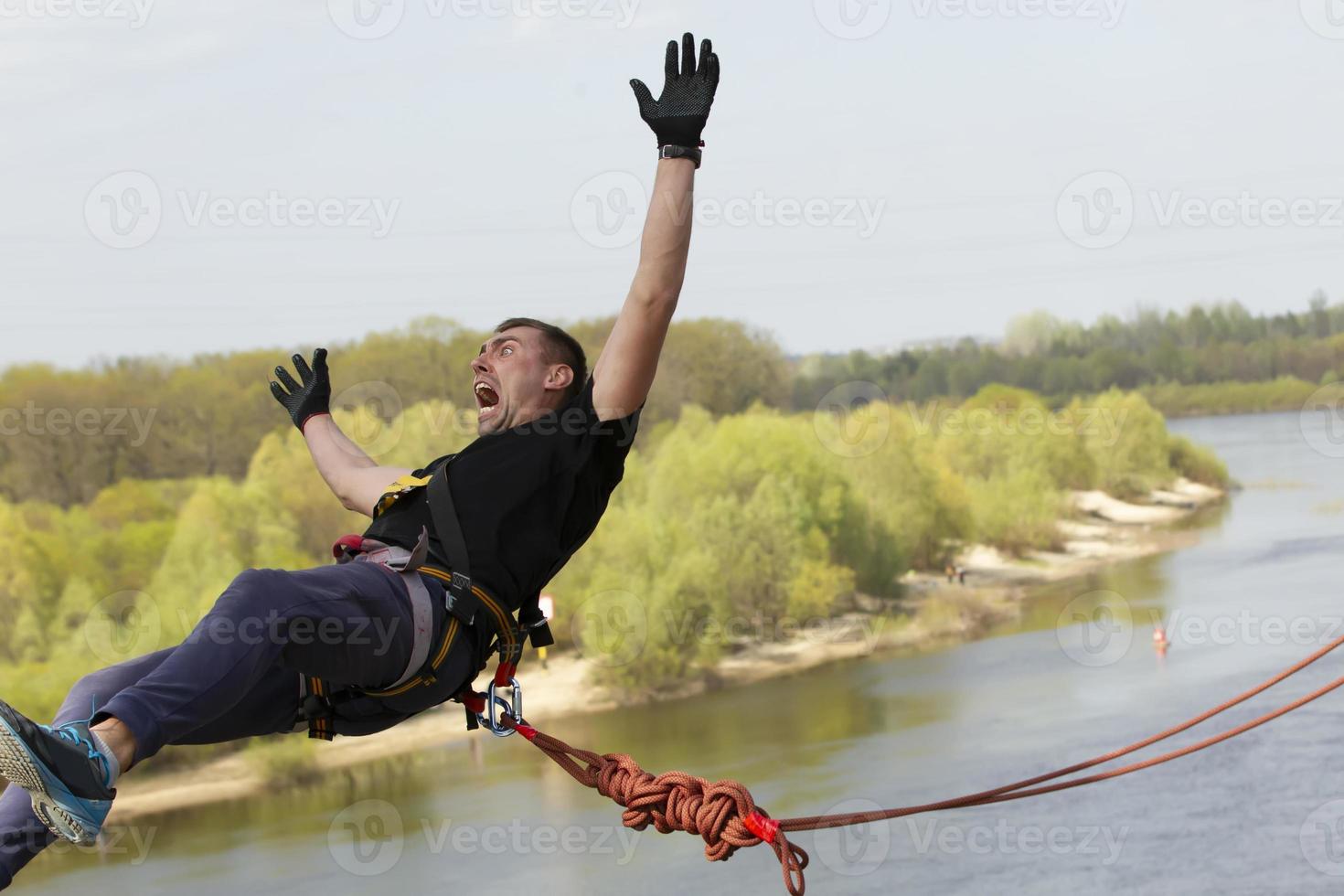 een Mens maakt een extreem springen van een brug Aan een touw. foto