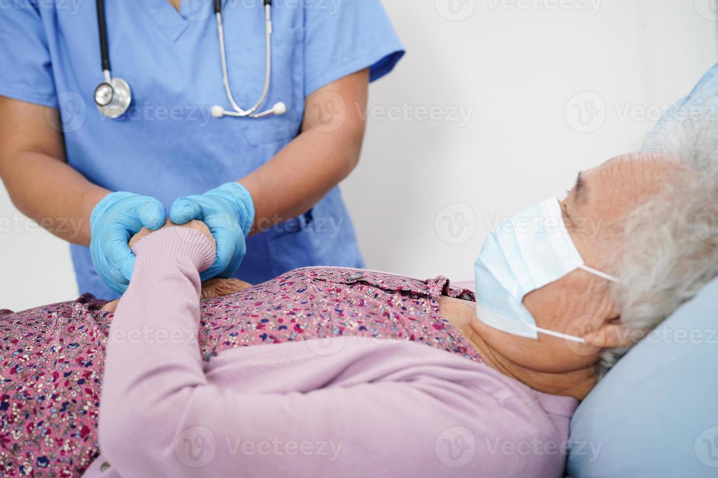arts controleert aziatische oudere senior vrouwelijke patiënt die een masker draagt om het covid-coronavirus te beschermen. foto