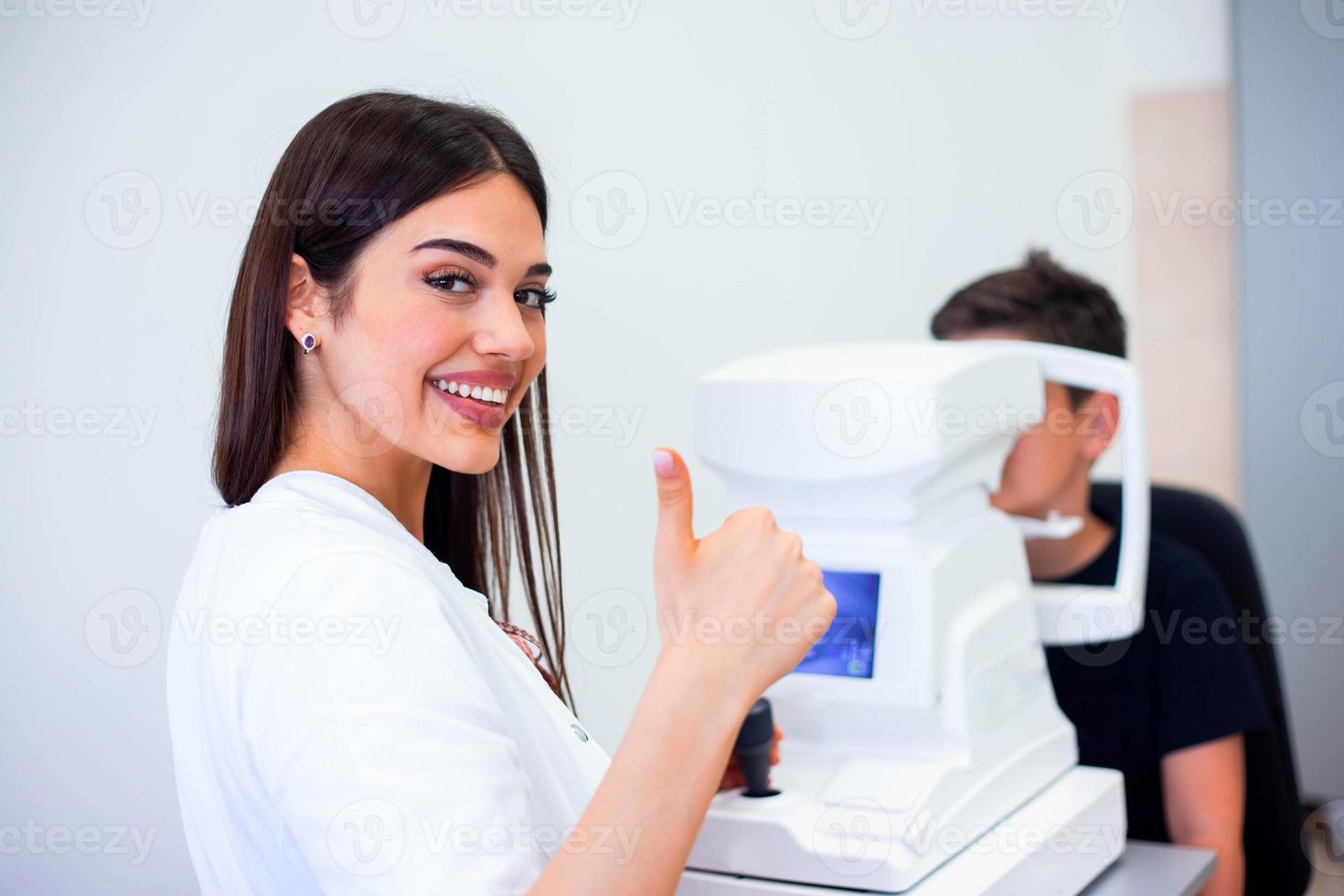 vrouw oogarts gebruik makend van machine voor controle oog zicht in kliniek. weinig jongen op zoek Bij uitrusting en dokter testen oog leerling in optisch op te slaan. concept van oog zorg en Gezondheid. foto