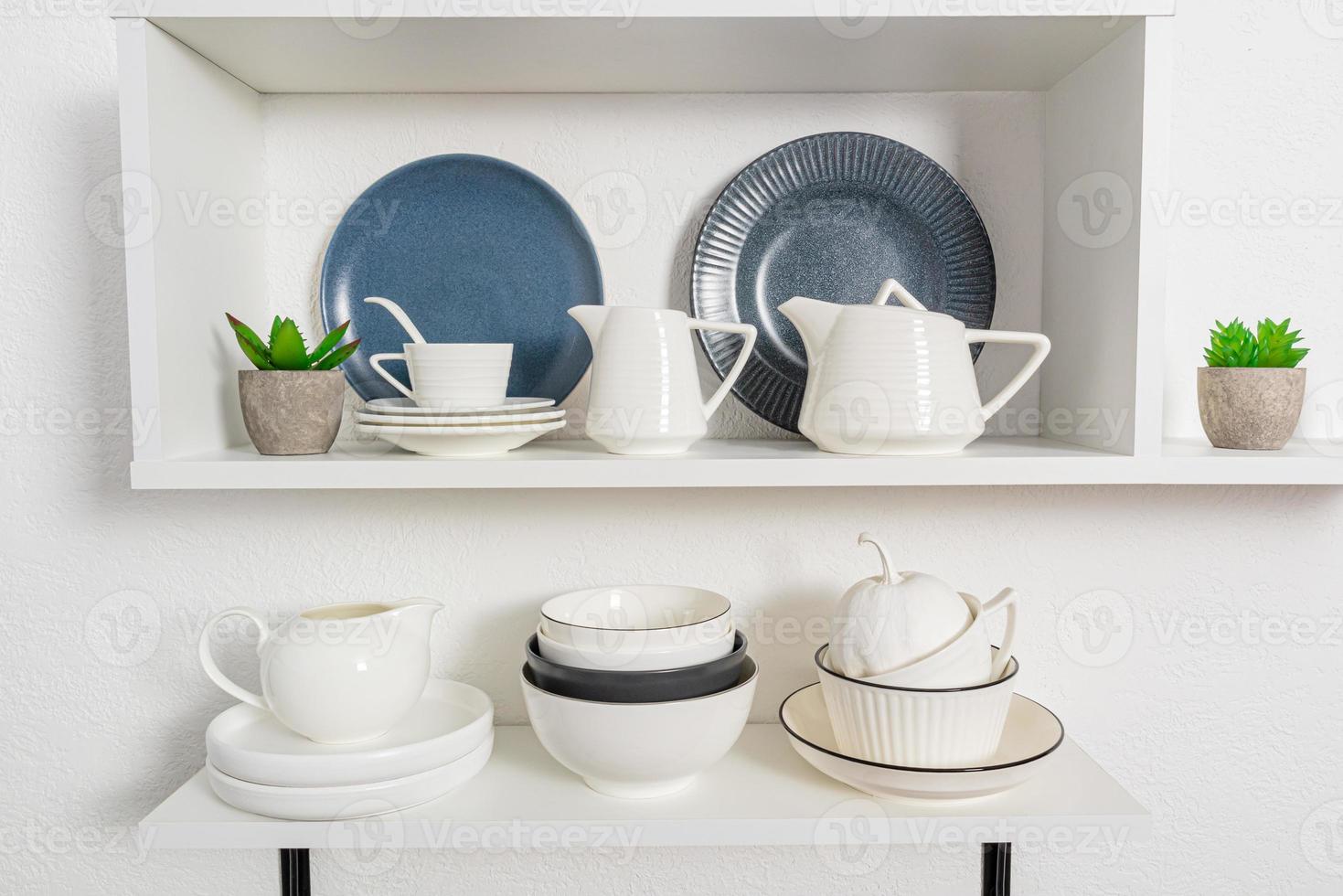 voorgrond visie, detailopname van Open keuken schappen met porselein en keramisch gebruiksvoorwerpen. elegant keuken achtergrond in wit tonen. foto