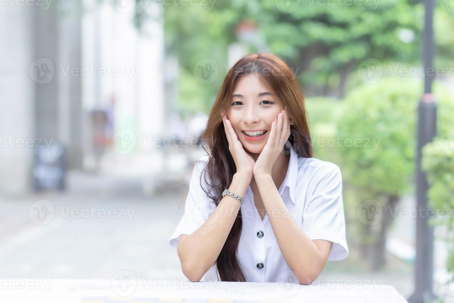 jong Thais Universiteit leerling meisje vervelend leerling uniform terwijl zittend en glimlachen in de Universiteit foto