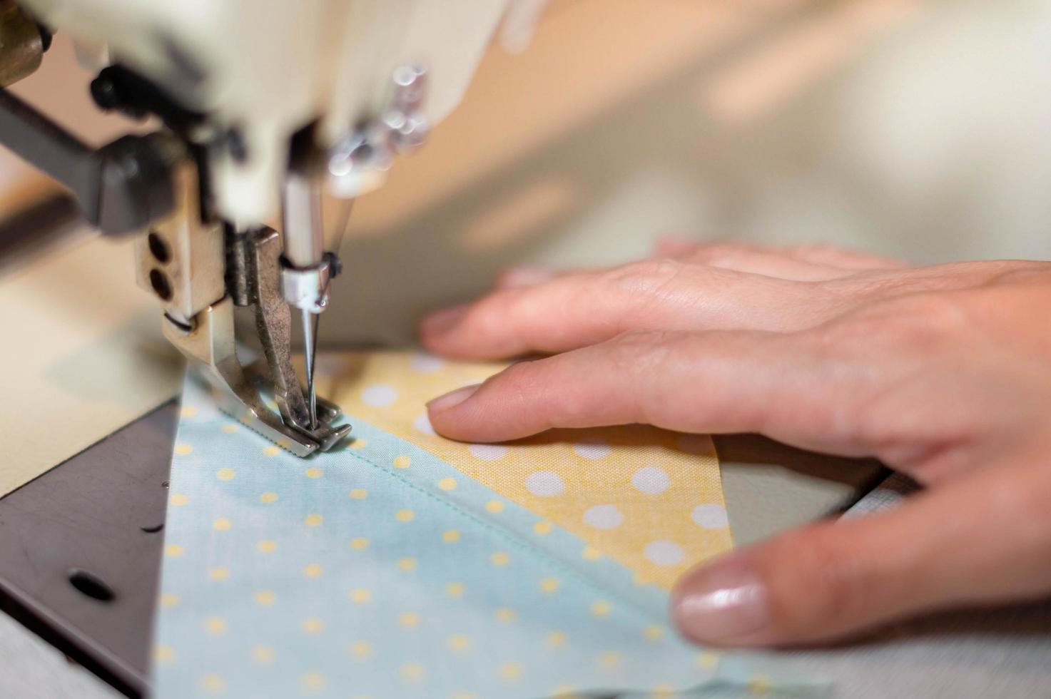 detailopname de vrouw hand- gebruik naaien machine en katoen kleding stof Bij de oud naaien machine met wijnoogst stijl. foto