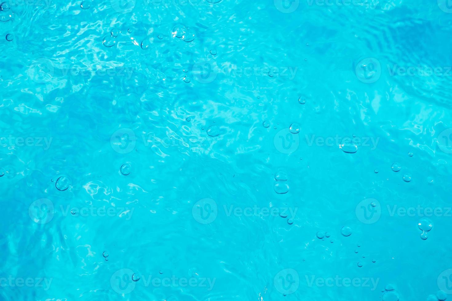 wazig transparant blauw gekleurd helder kalm water oppervlaktetextuur met spatten en bubbels. trendy abstracte natuur achtergrond. watergolven in zonlicht. water achtergrond foto