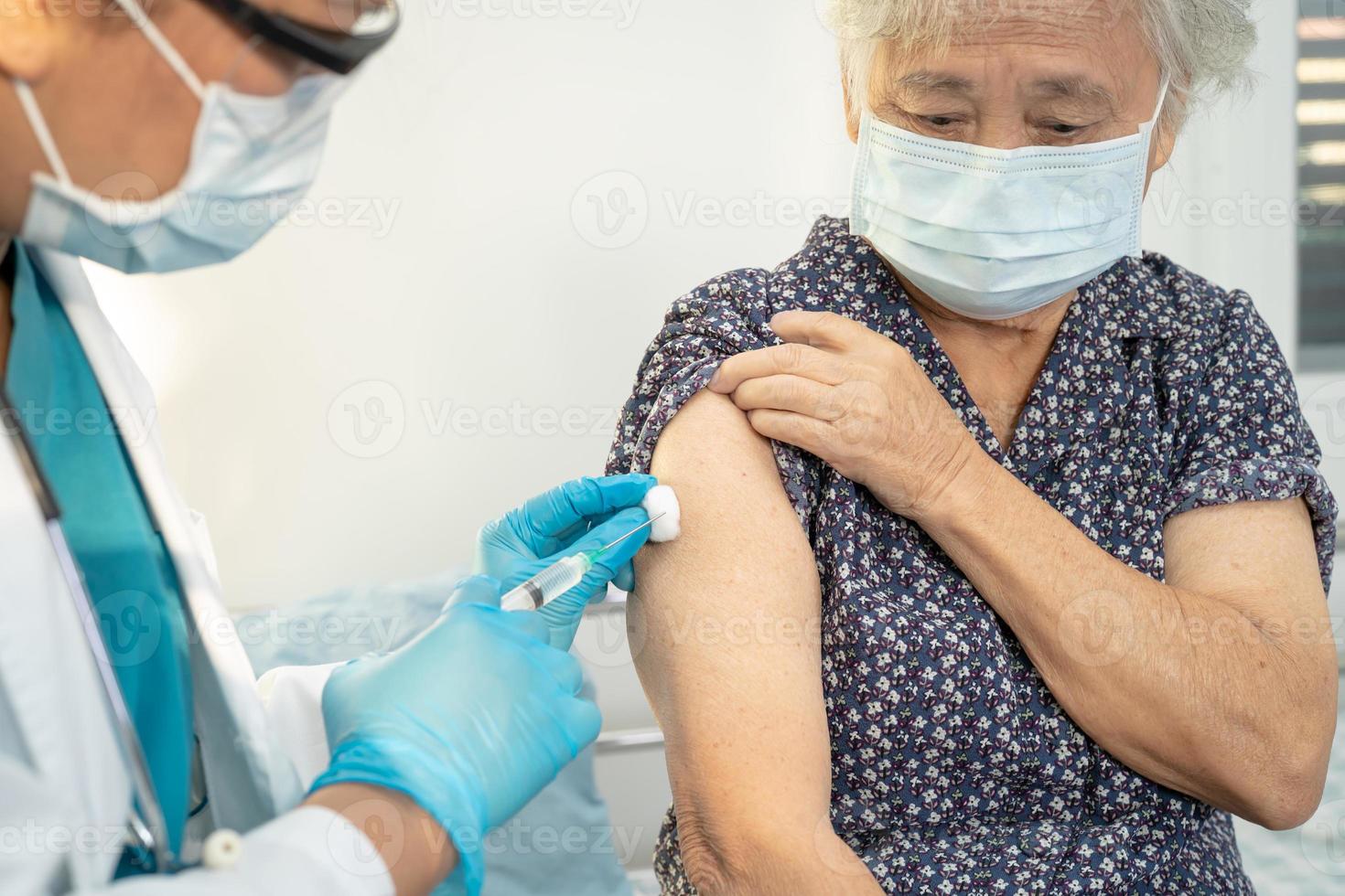 oudere aziatische senior vrouw met gezichtsmasker die covid19 of coronavirusvaccin krijgt door een arts, maakt injectie. foto