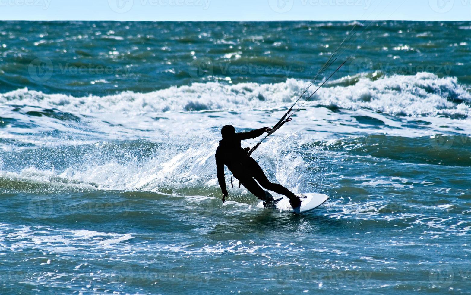 silhouet van een kitesurfer Aan golven van een zee foto
