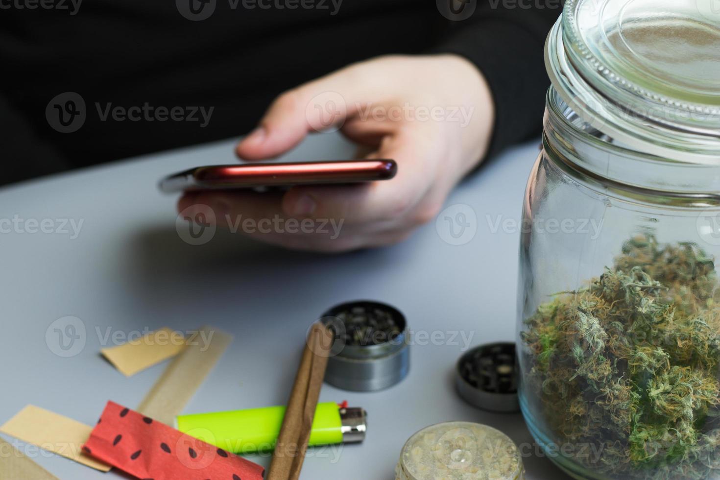 Mens Holding telefoon De volgende naar hennep en roken accessoires. buying marihuana en onkruid online. bedrijf concept foto