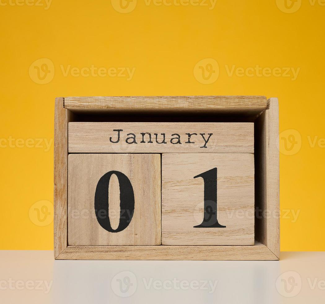 houten kalender gemaakt van kubussen Aan een geel achtergrond. datum januari 1e, begin van de jaar foto