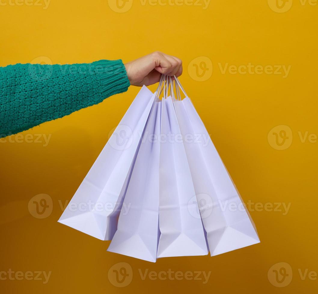 vrouw hand- houdt een wit papier beschikbaar zak met handvatten voor boodschappen en kleren. recyclebaar verpakking. nul afval. uitverkoop foto