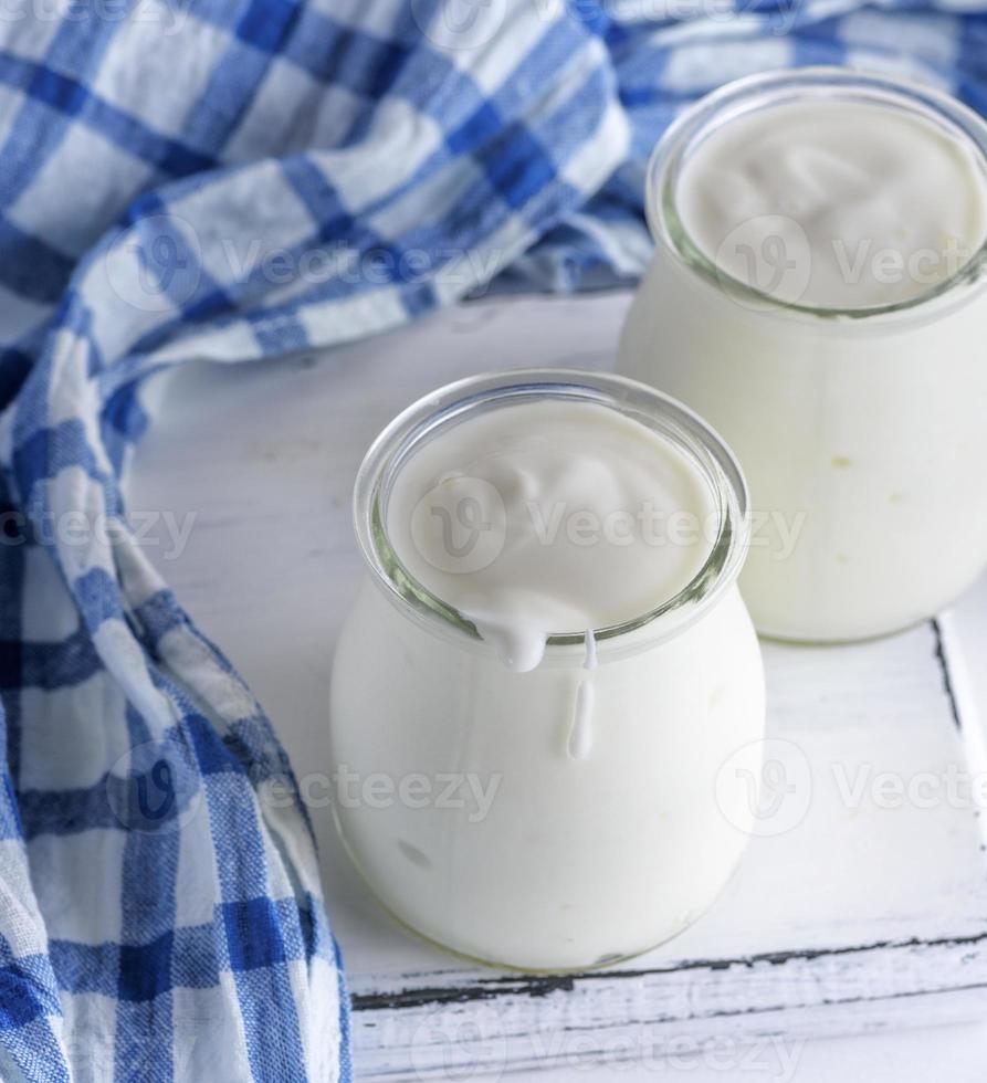 glas potten met eigengemaakt yoghurt Aan een wit houten bord foto