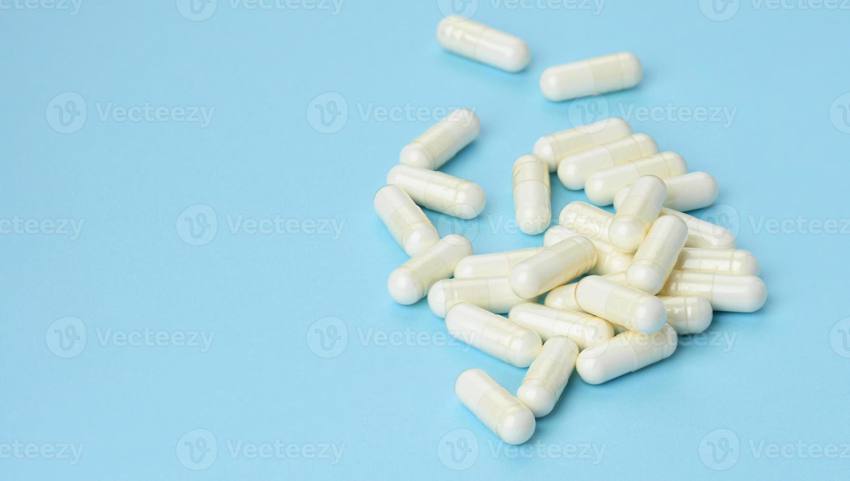 medisch poeder in wit capsules Aan een blauw achtergrond. behandeling pillen, voedingswaarde supplementen foto