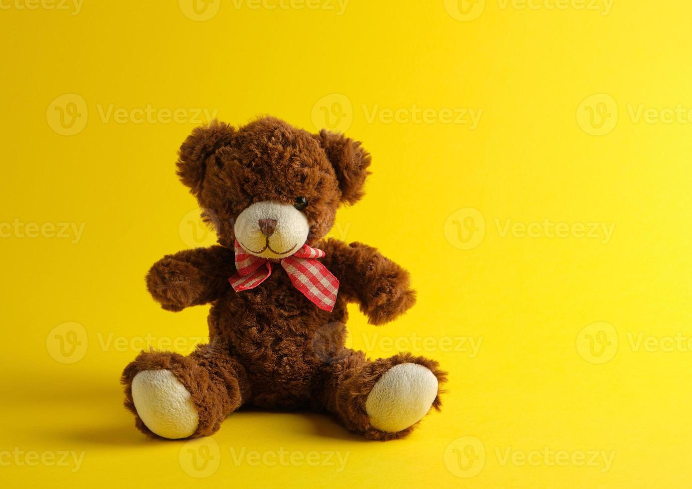 bruin teddy beer zittend Aan een geel achtergrond foto