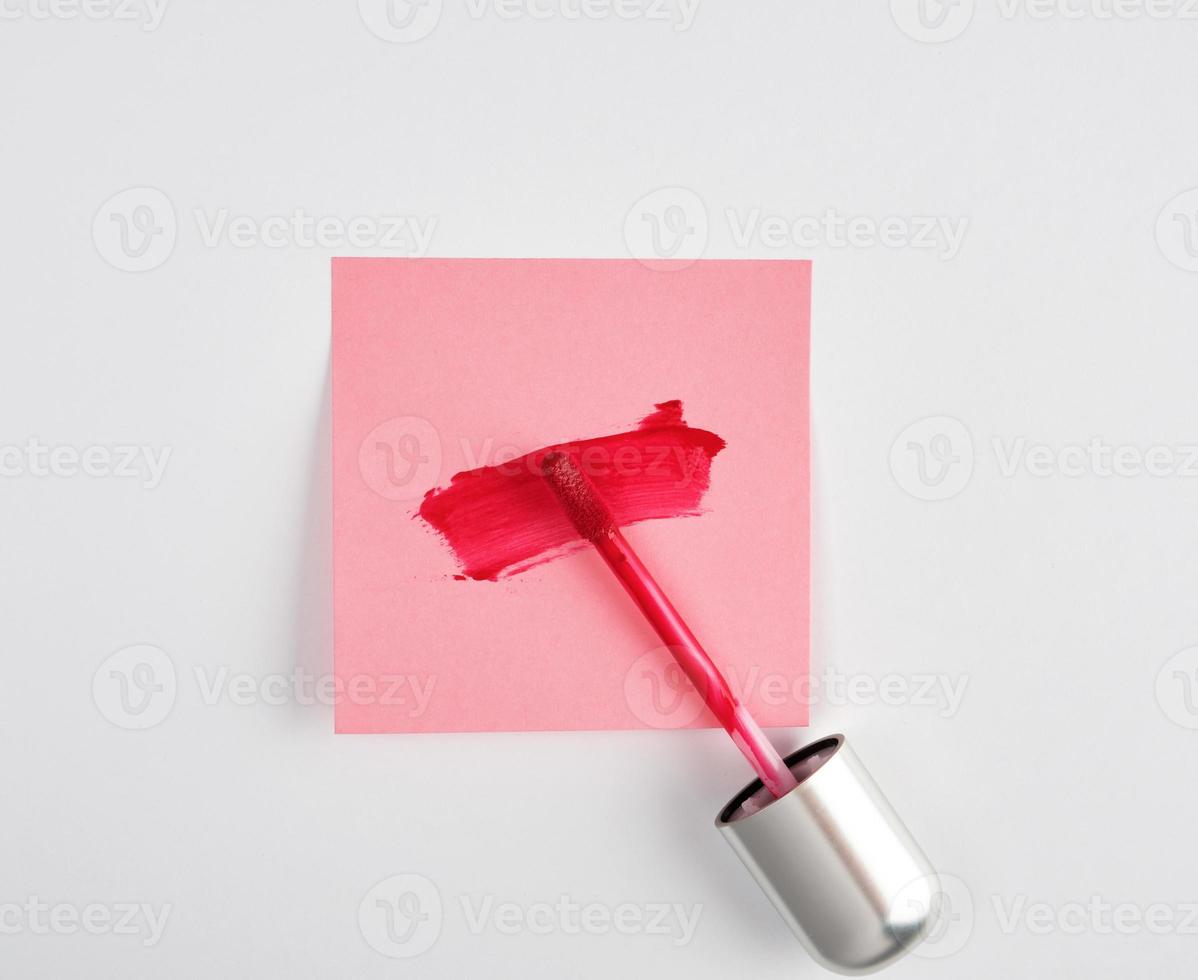 vloeistof lippenstift en een smeren van rood lippenstift Aan een roze papier sticker foto