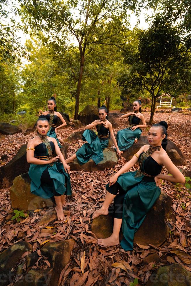 een groep van Indonesisch dansers zittend prachtig Aan de rots met bruin bladeren in de achtergrond binnen de Woud foto