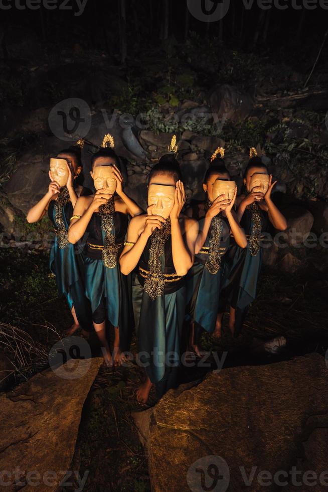 een groep van Aziatisch Dames vervelend een houten maskers in groen kostuums terwijl staand tussen de rotsen binnen de Woud foto