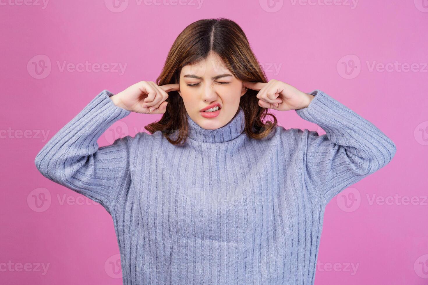 portret van geërgerd vrouw plakken plug vingers in oren niet luisteren naar luid lawaai geluid geïsoleerd over- roze achtergrond foto