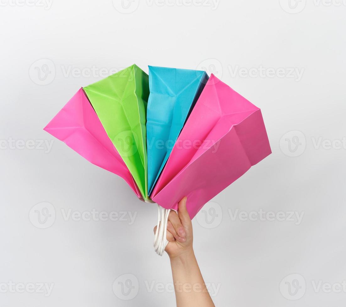 vrouw hand- Holding vier gekleurde papier boodschappen doen verpakking Tassen foto