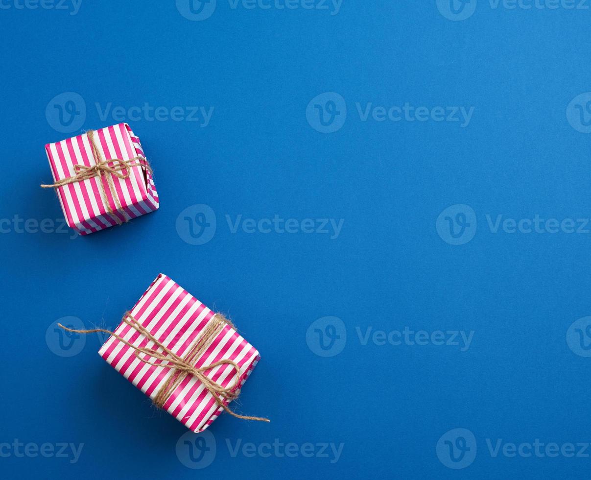 twee cadeaus verpakt in roze gestreept papier Aan een blauw achtergrond foto