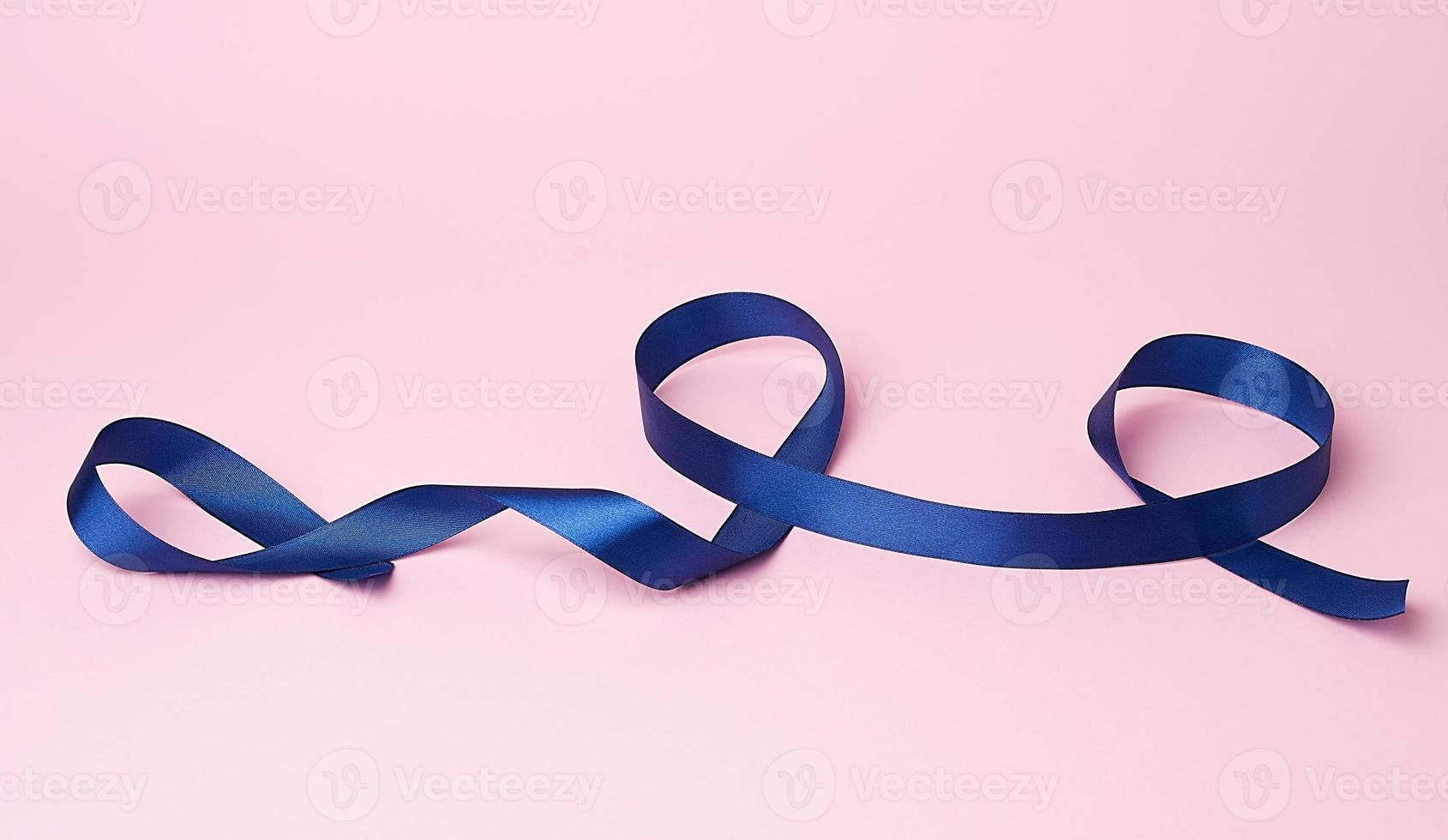 donker blauw zijde lint gedraaid in loops Aan een roze achtergrond foto