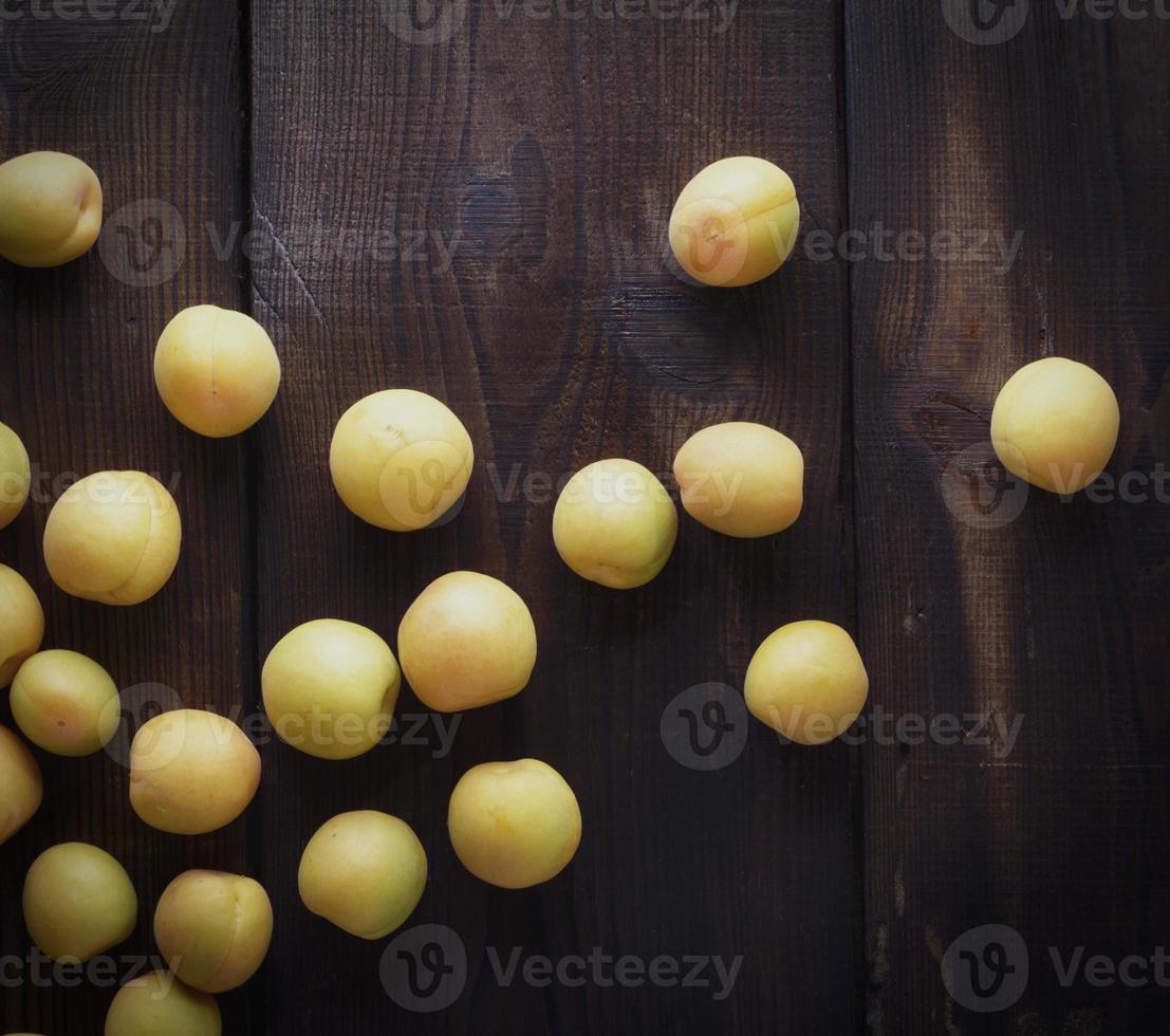 verspreide rijp geel abrikozen Aan een bruin houten tafel foto