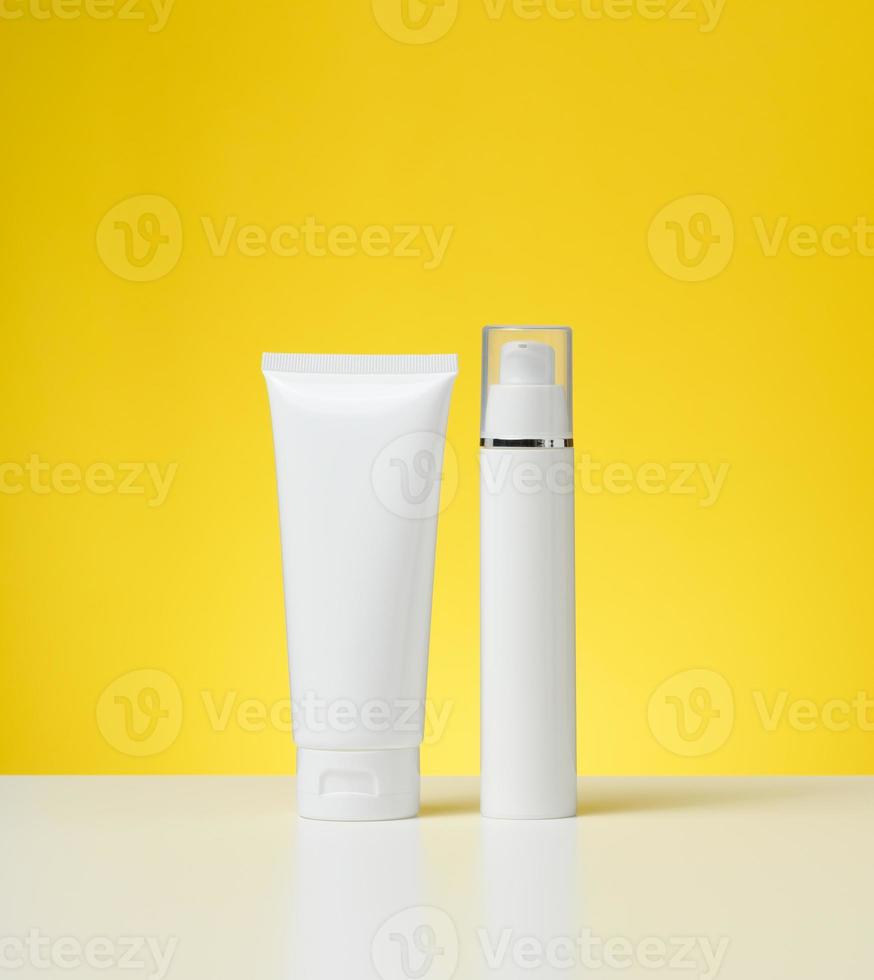 plastic wit fles met een dispenser en een buis met een deksel Aan een wit tafel, geel achtergrond. verpakking voor cosmetica, branding en Product Promotie foto