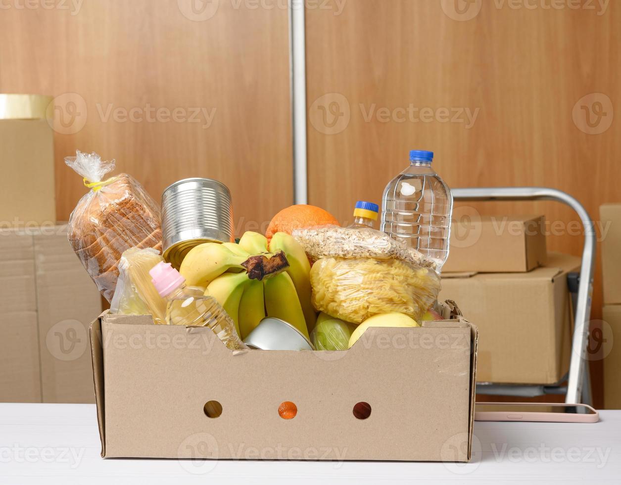 karton doos met divers producten, fruit, pasta, zonnebloem olie in een plastic fles en behoud foto