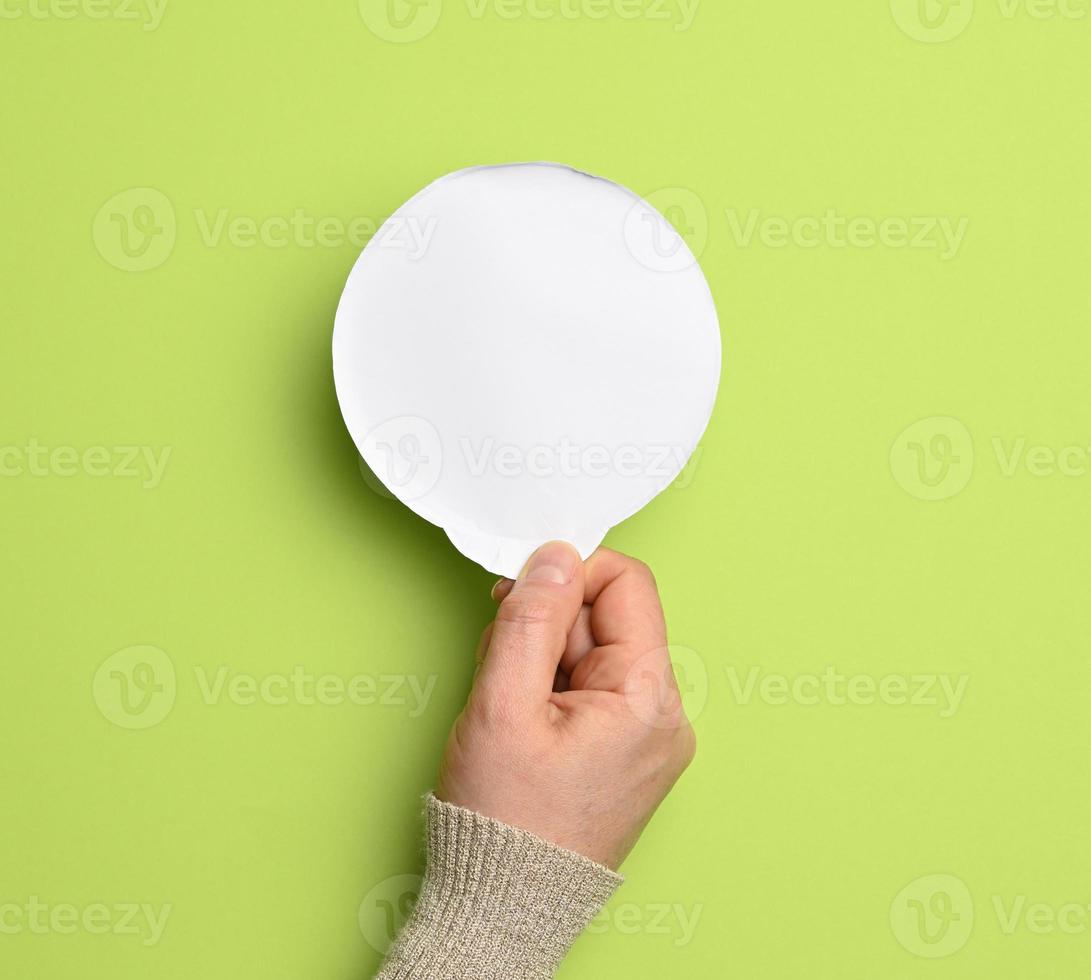 vrouw hand- Holding een ronde wit papier yoghurt deksel Aan een groen achtergrond foto