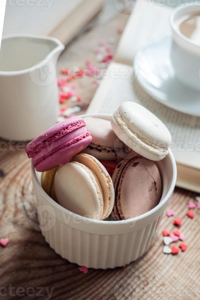 bitterkoekjes in een kom en een kop van koffie, een boek Aan de achtergrond van klein harten Aan een houten achtergrond, top visie foto