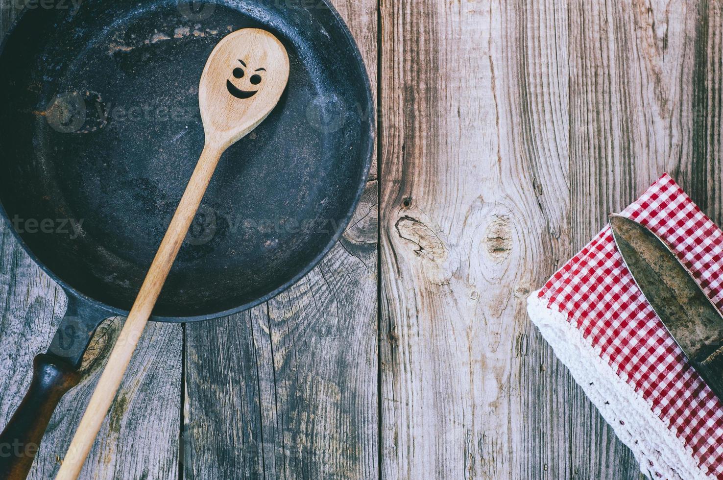 zwart frituren pan met een houten lepel Aan een grijs tafel foto