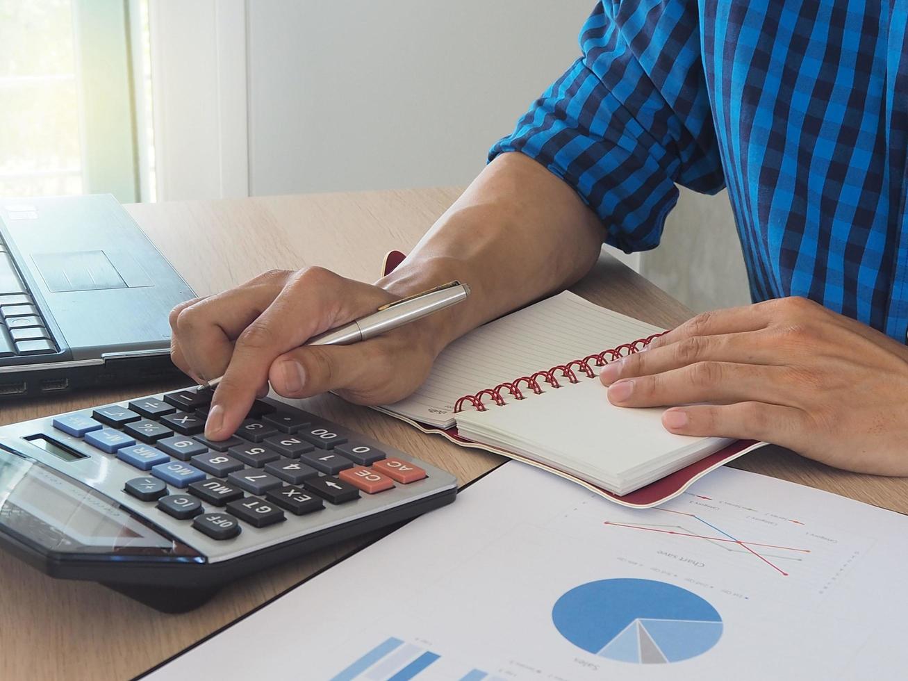 accounting concept Mannen hand- toepassingen een rekenmachine naar berekenen statistieken. over zijn werk berekenen de gegevens in de functie. foto