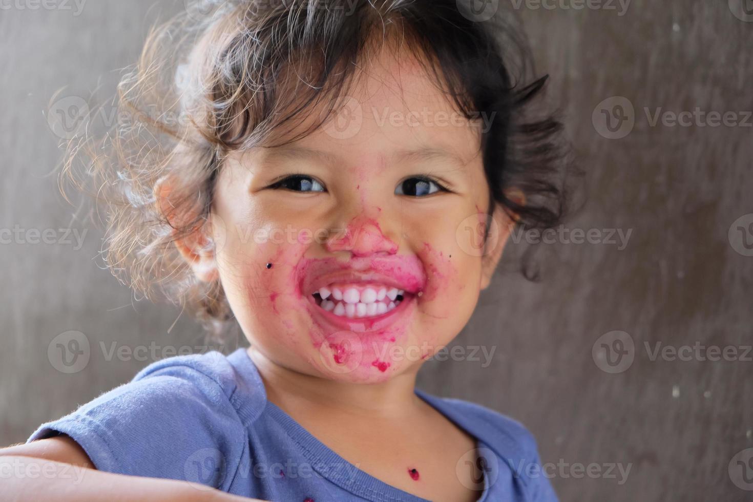 detailopname van schattig gekruld jongen genieten van draak fruit met rommelig rood gezicht foto