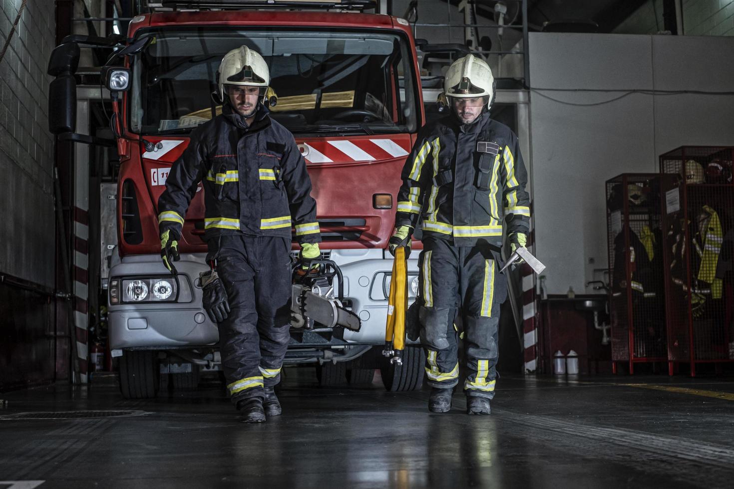 brandweerlieden die de post verlaten, uitgerust en met het gereedschap om de brand te blussen foto