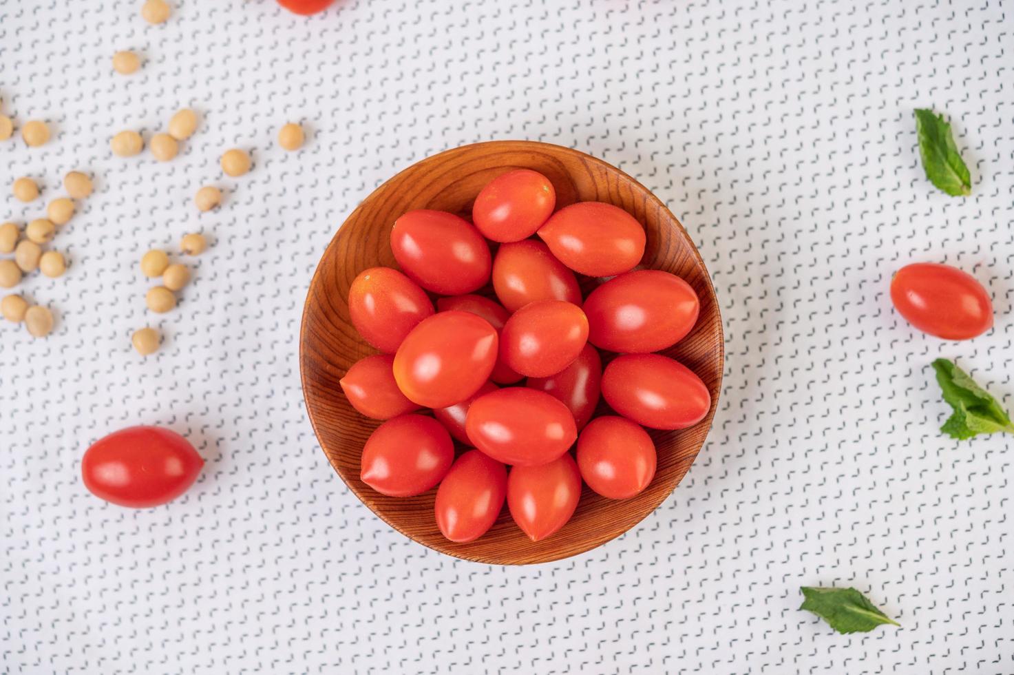 tomaten in een houten beker op een witte doek foto