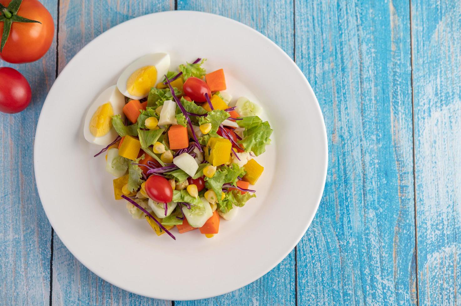 frisse salade op een witte plaat met een sandwich en tomaten foto