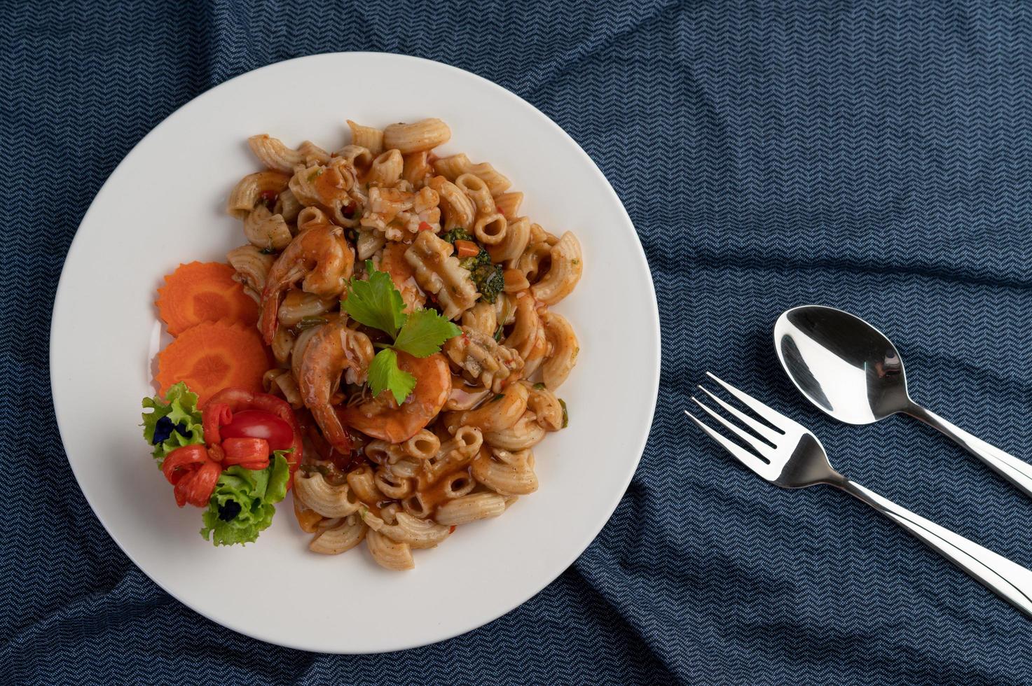 garnalen en macaroni met wortelen, tomaten en salade foto