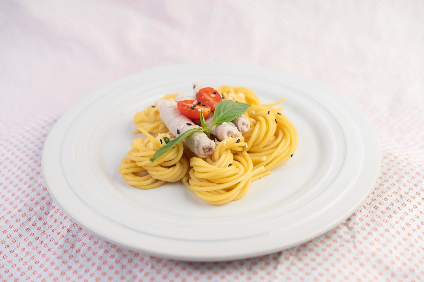 vergulde spaghetti en varkensvlees gerangschikt op een witte plaat foto