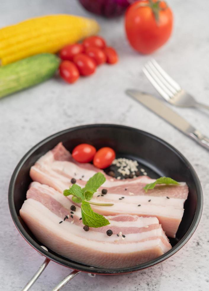 buikspek in een pan met peperzaadjes, tomaten en kruiden foto