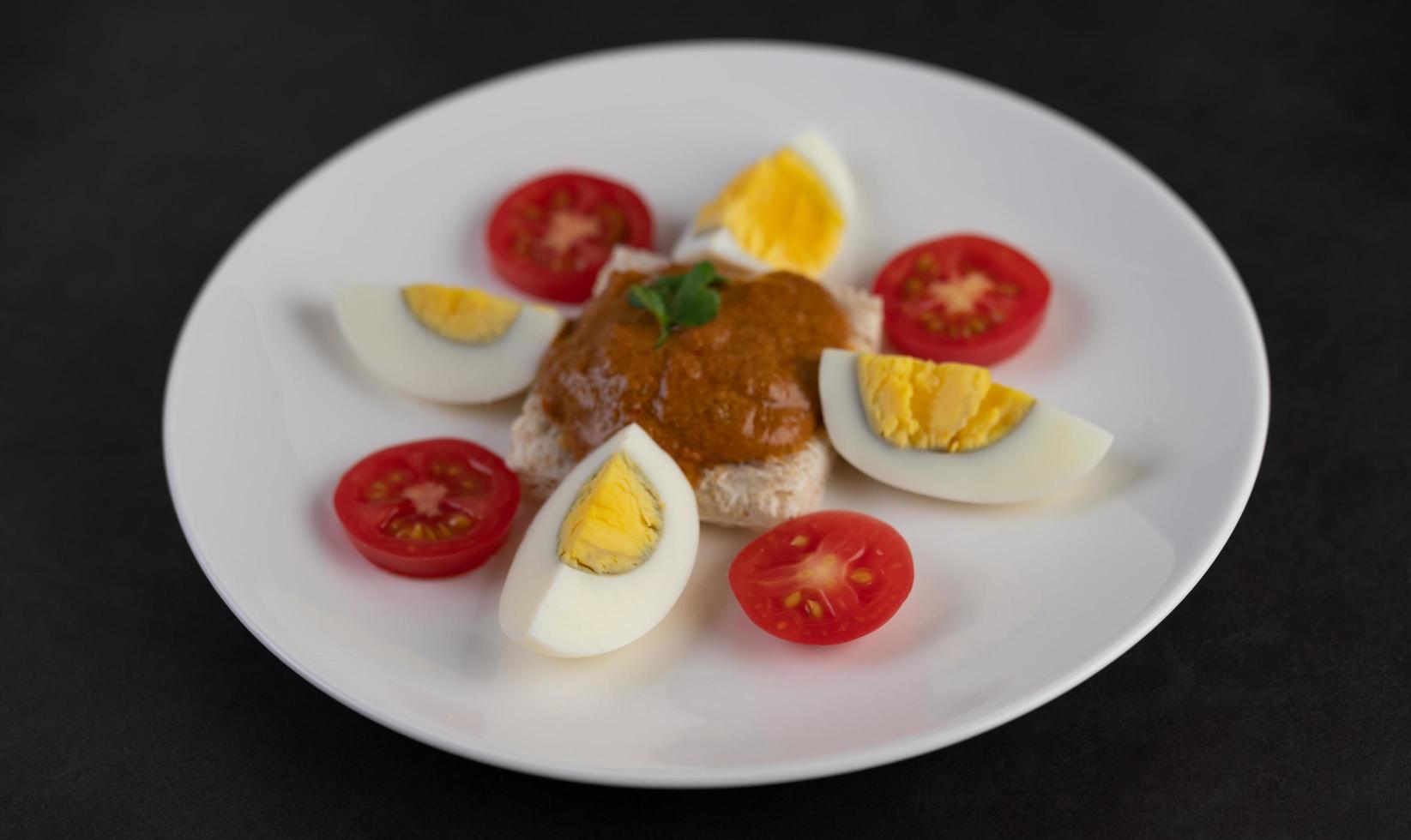 brood gegarneerd met chilipasta met gekookte eieren en tomaten foto