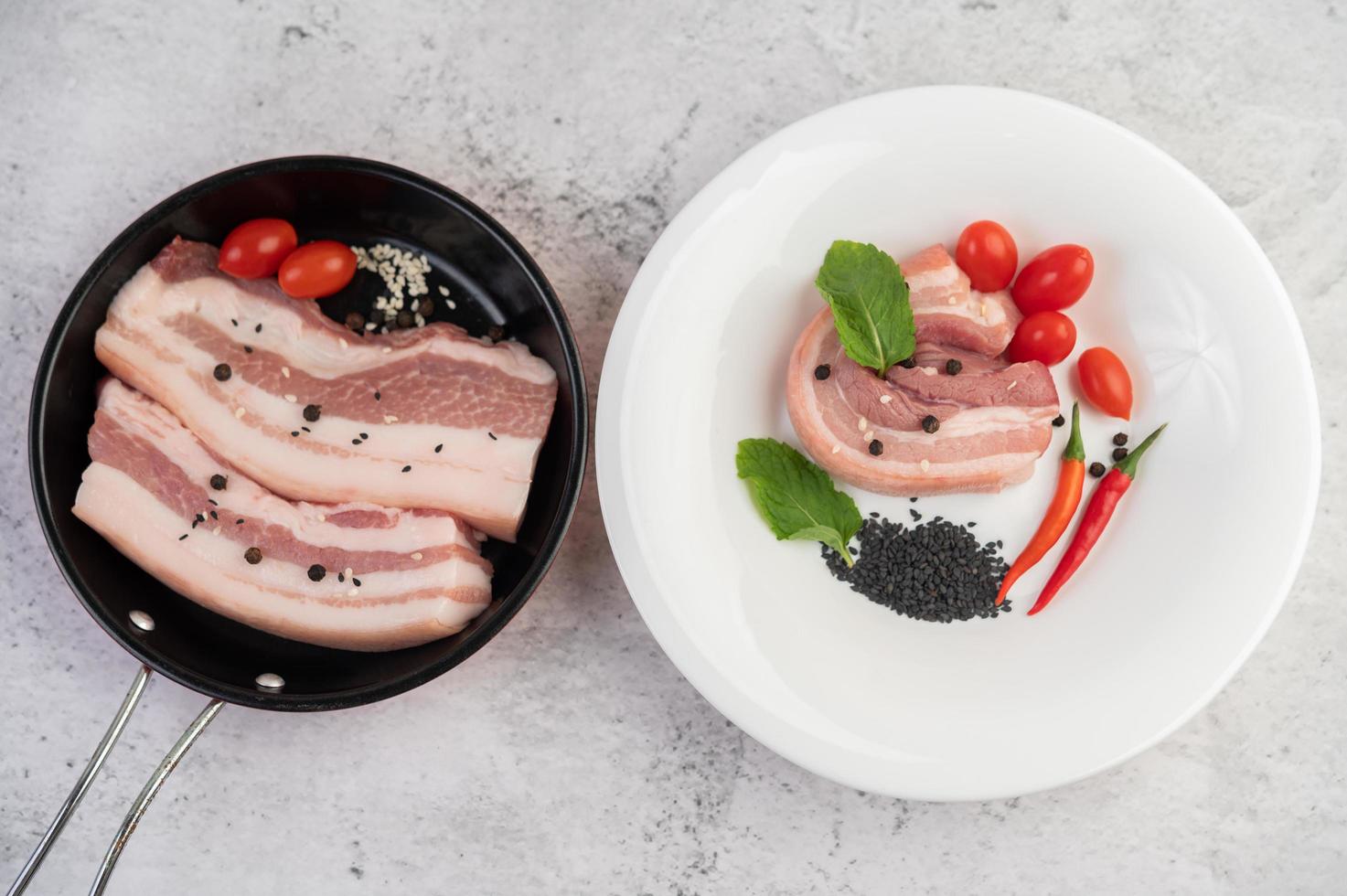 buikspek in een pan met peperzaadjes, tomaten en kruiden foto