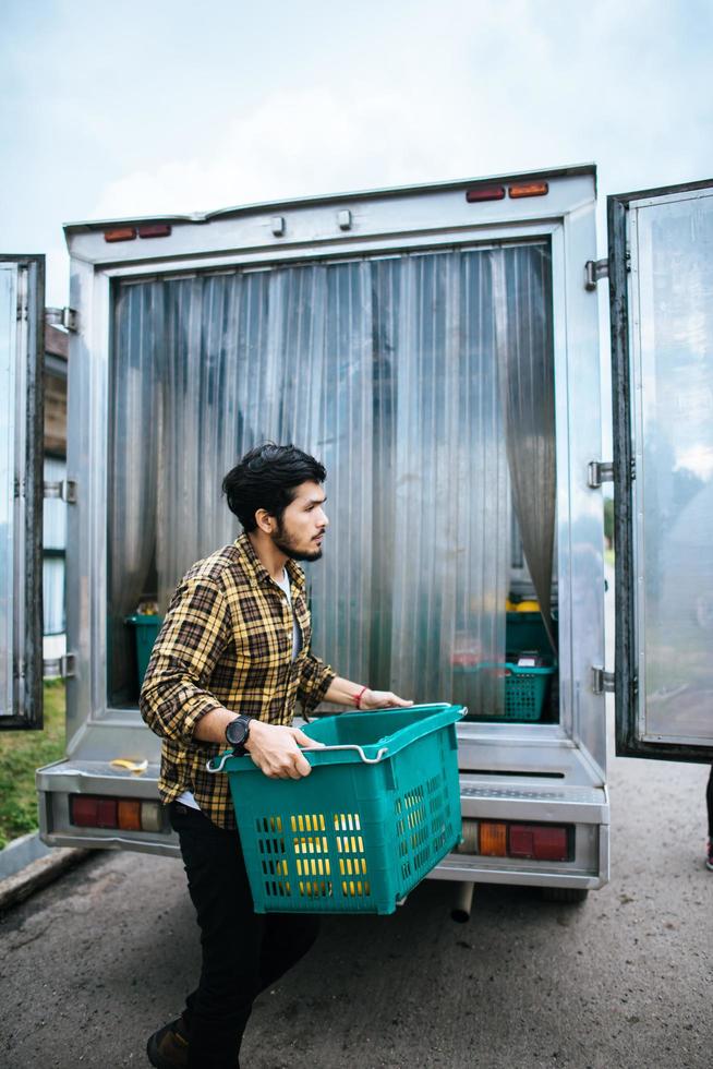 portret van een hipster boer met een doos met fruit te koop op de markt foto