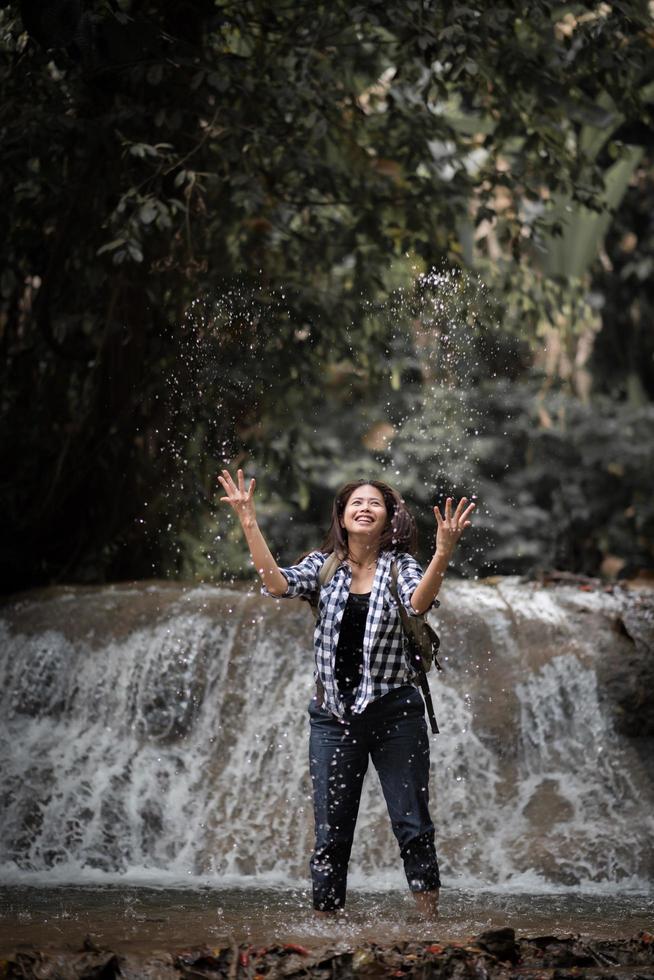 jonge vrouw met plezier onder een waterval in het bos foto