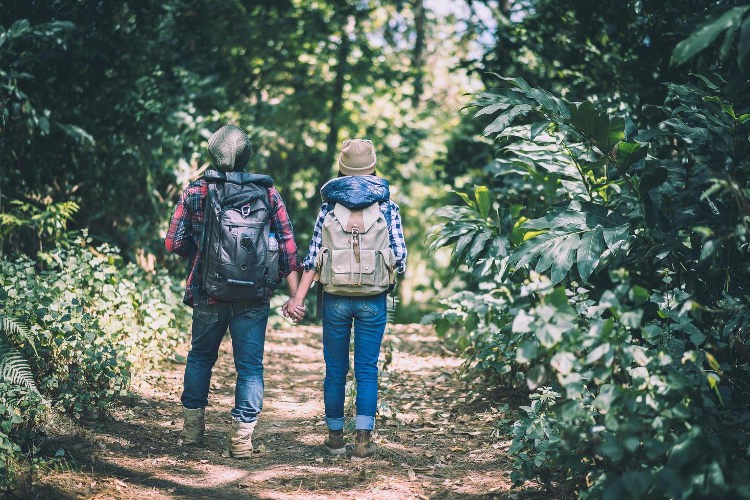 jong koppel wandelen met rugzakken in het bos foto